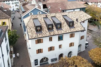 a large white building with a tree in front of it at Schmitte am Sonnenwirtsplatz Eppan in South Tyrol, perfect starting point for bike and hike in Appiano sulla Strada del Vino