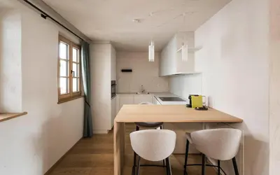 a small kitchen with a wooden table and chairs at Schmitte am Sonnenwirtsplatz Eppan in South Tyrol, perfect starting point for bike and hike in Appiano sulla Strada del Vino