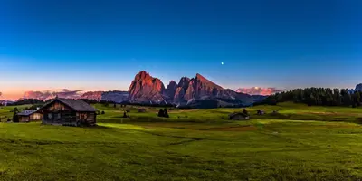 an old house in a field with mountains in the background at Chalet Villa Carolina in Selva di Val Gardena