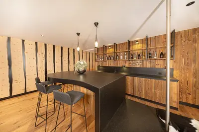 a wine tasting room with a black counter and stools at Chalet Villa Carolina in Selva di Val Gardena