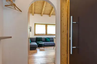 an open door to a living room with a blue couch at Alpine View Plan de Corones in Sorafurcia