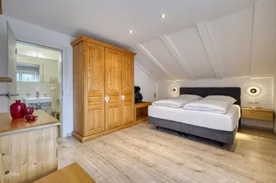 a bedroom with a king sized bed and a bathroom at Appartements Kreuzwegerhof in Lana
