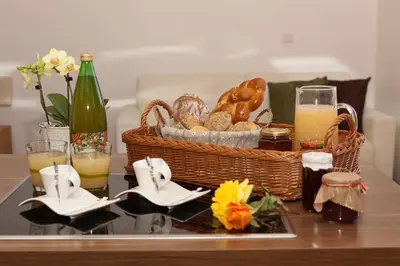 a table with a basket of bread and a basket of orange juice at Appartements Kreuzwegerhof in Lana