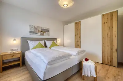a bedroom with a large bed with white sheets and green pillows at Appartements Kreuzwegerhof in Lana