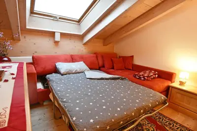 a living room with a couch and a bed at Mansarda Le Genziane di Fiemme in Cavalese