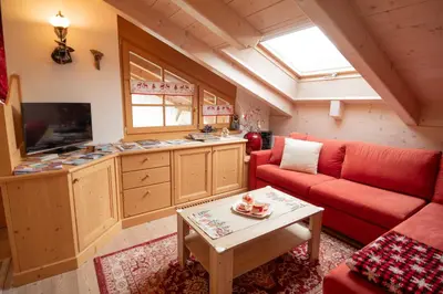 a living room with a red couch and a table at Mansarda Le Genziane di Fiemme in Cavalese
