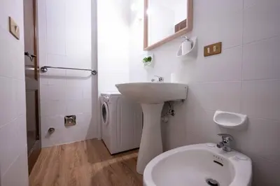 a white bathroom with a sink and a toilet at Cesa Alpes 3 in Campitello di Fassa