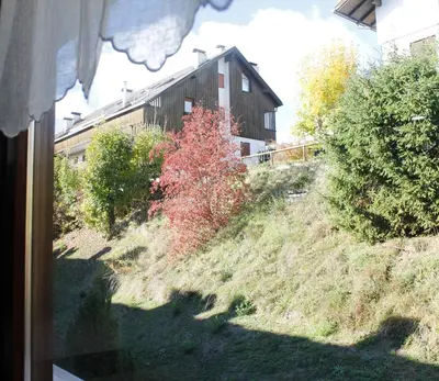 a house on a hill with a red tree at IL CERVO - 2 camere, garage Dolomiti Affitti in Cavalese