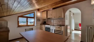 a kitchen with a table and a wooden ceiling at Cesa Fortunato in Canazei