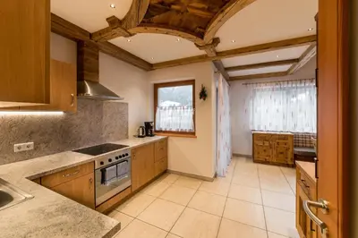 a large kitchen with wooden cabinets and a ceiling at Haus Alpenjuval in Fundres