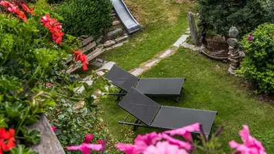 a garden with a table and some pink flowers at Haus Alpenjuval in Fundres