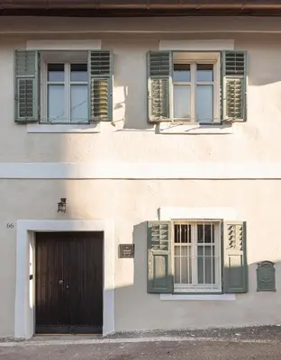 a building with green shuttered windows and a door at Smart Suites Kaltern - Apartments am Kalterer See in Caldaro