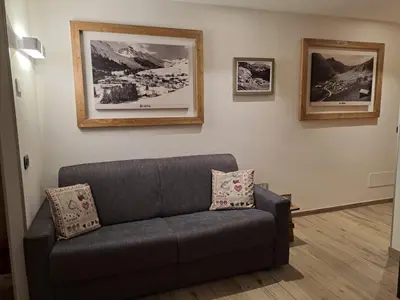 a living room with a couch and pictures on the wall at Appartamento Césa Ines in Arabba