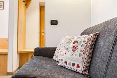 a pillow sitting on a gray couch in a room at Appartamento Césa Ines in Arabba