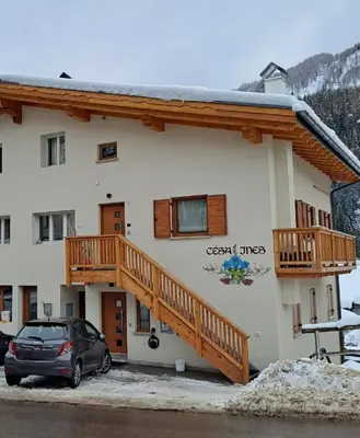a house with a balcony and a car parked in front at Appartamento Césa Ines in Arabba
