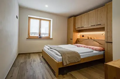a bedroom with a bed in a room with a window at Appartamento Césa Ines in Arabba