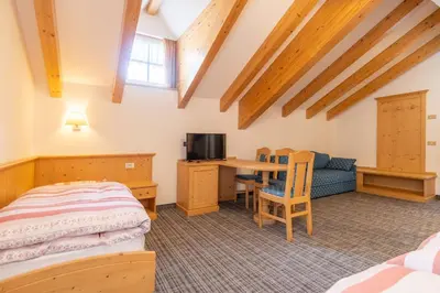 a bedroom with a bed and a desk and a tv at Albergo Canazei in Canazei