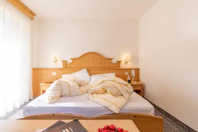 a bedroom with a bed with white sheets on it at Albergo Canazei in Canazei