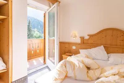 a bedroom with a bed and a balcony at Albergo Canazei in Canazei