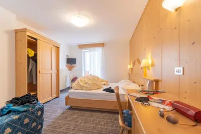 a bedroom with a bed and a desk in a room at Albergo Canazei in Canazei