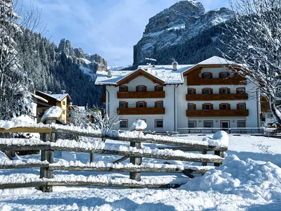 a building with a fence in the snow at Albergo Canazei in Canazei