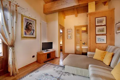 a living room with a couch and a tv at Hotel Leonardo in Moena