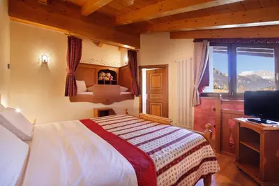 a bedroom with a bed and a television and a window at Hotel Leonardo in Moena