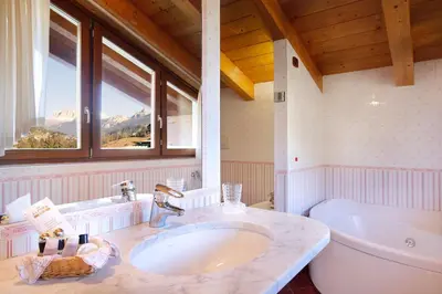 a bathroom with a sink and a toilet and windows at Hotel Leonardo in Moena