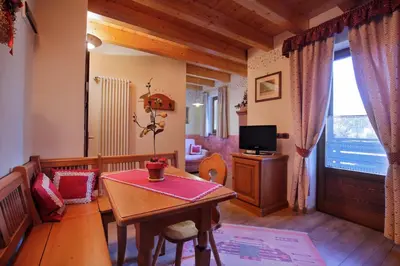 a living room with a table and a television at Hotel Leonardo in Moena