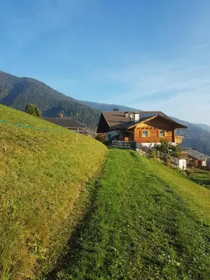 a house on top of a hill with a grass field at Ferienwohnung Maiernhof Bauernhof Ultental in San Pancrazio dʼUltimo