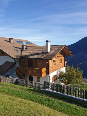 a house on top of a hill with a fence at Ferienwohnung Maiernhof Bauernhof Ultental in San Pancrazio dʼUltimo