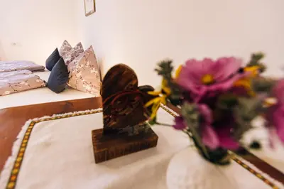 a table with a vase of flowers next to a bed at Stimpflhof in Aldino