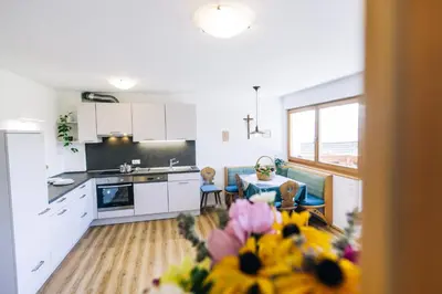 a kitchen with white cabinets and a table with flowers at Stimpflhof in Aldino