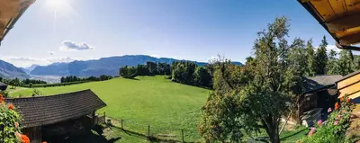 a large green field with mountains in the background at Stimpflhof in Aldino