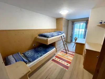 a room with two bunk beds and a table at Ciasa Rossi in Soraga