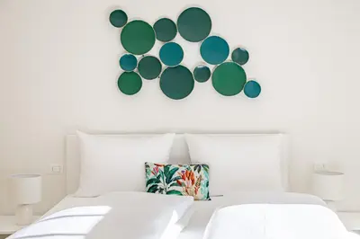 a white bed with a pillow and a mirror on the wall at Italyescapes Emma 11 in Merano