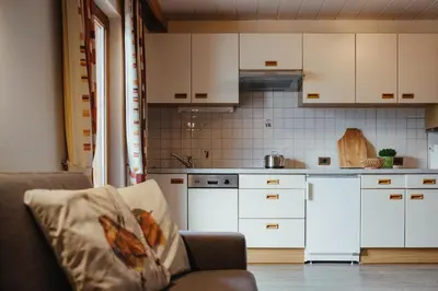 a kitchen with white cabinets and a couch at Oberaldoss Residence Wellness in Santa Cristina in Val Gardena