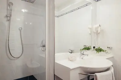 a white bathroom with a sink and a shower at Oberaldoss Residence Wellness in Santa Cristina in Val Gardena