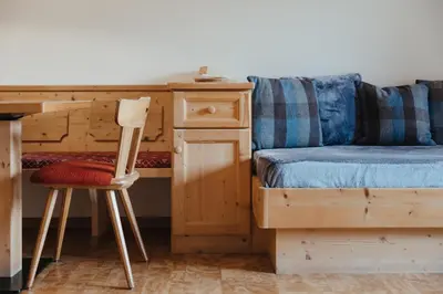 a bedroom with a bed and a desk and a chair at Oberaldoss Residence Wellness in Santa Cristina in Val Gardena
