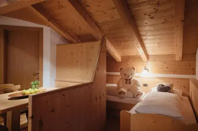 a teddy bear sitting on a bed in a wooden room at Oberaldoss Residence Wellness in Santa Cristina in Val Gardena