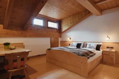 a bedroom with a large wooden bed in a room with wooden ceilings at Oberaldoss Residence Wellness in Santa Cristina in Val Gardena