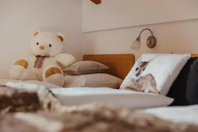 a teddy bear sitting on top of a bed at Oberaldoss Residence Wellness in Santa Cristina in Val Gardena