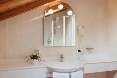 a bathroom with a sink and a mirror and a tub at Oberaldoss Residence Wellness in Santa Cristina in Val Gardena