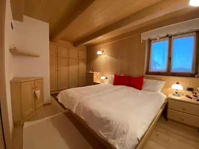 a bedroom with a large white bed with red pillows at Cozy Mountain Chalet in Cavalese