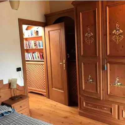 a bedroom with wooden furniture and a book shelf at Mansarda su due livelli nel cuore delle Dolomiti in San Vito di Cadore