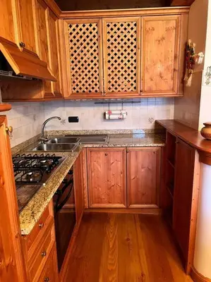 a kitchen with wooden cabinets and a sink and a stove at Mansarda su due livelli nel cuore delle Dolomiti in San Vito di Cadore