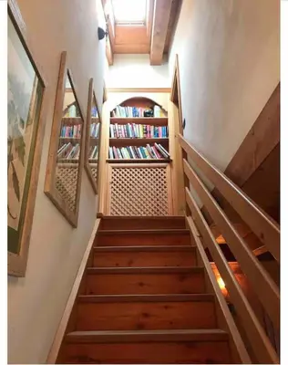 a staircase leading to a room with bookshelves at Mansarda su due livelli nel cuore delle Dolomiti in San Vito di Cadore