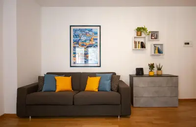 a living room with a couch with yellow and blue pillows at Tranquillo bilocale vicino al centro storico in Bolzano