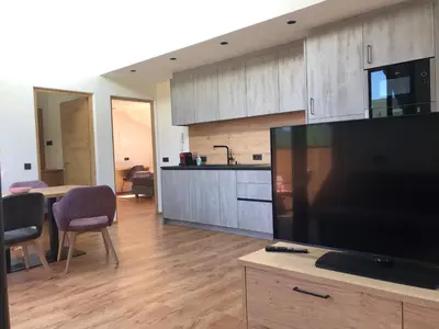 a living room with a large television and a kitchen at Appartements Pedescin in Ortisei