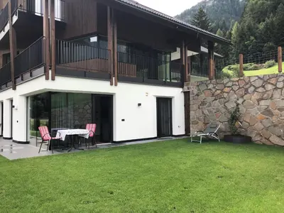 a house with a table and chairs in a yard at Appartements Pedescin in Ortisei